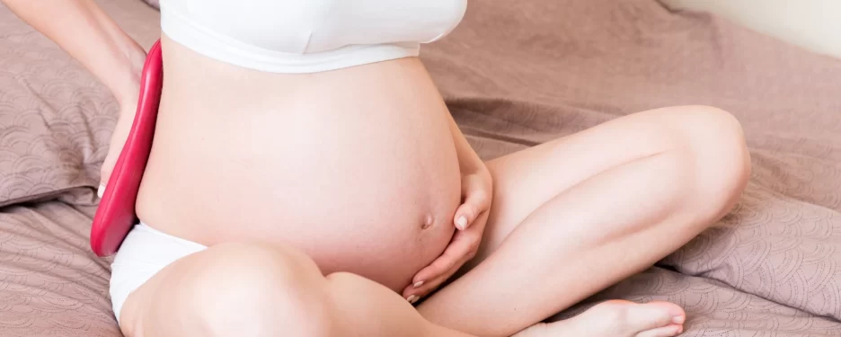 Pregnant woman applying heat therapy to her lower back pain