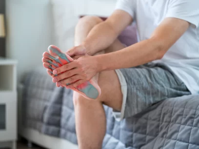Patient holding his painful foot due to plantar fasciitis in need of osteopathy, shockwave therapy, dry needling and sports massage to treat this condition